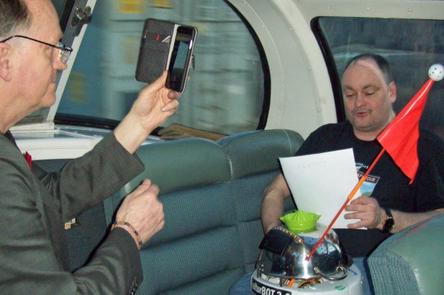 David Brydges, artistic director for the Great Canadian PoeTrain Tour as well as Pat Connors, one of the key organizers interacts with My kulturbot 3.0, the world's first robot poet to ride a train.